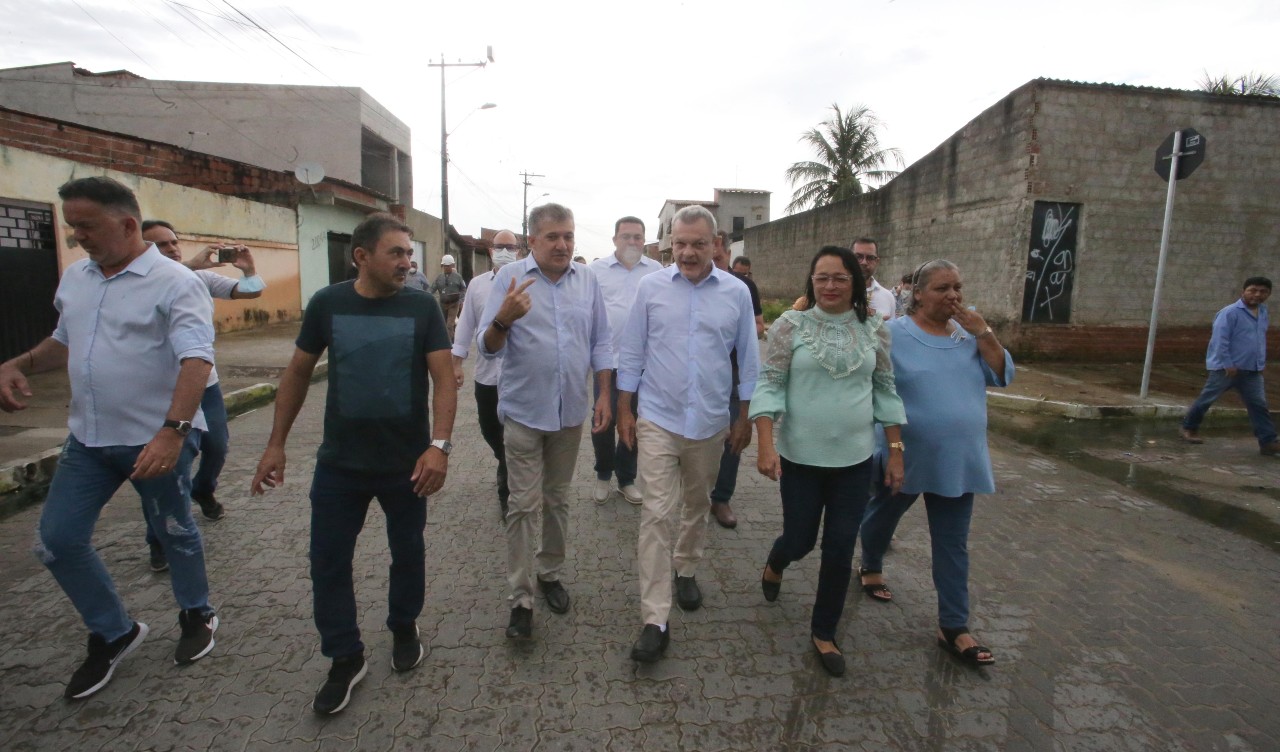 prefeito e um grupo de assessores caminha por uma rua urbanizada